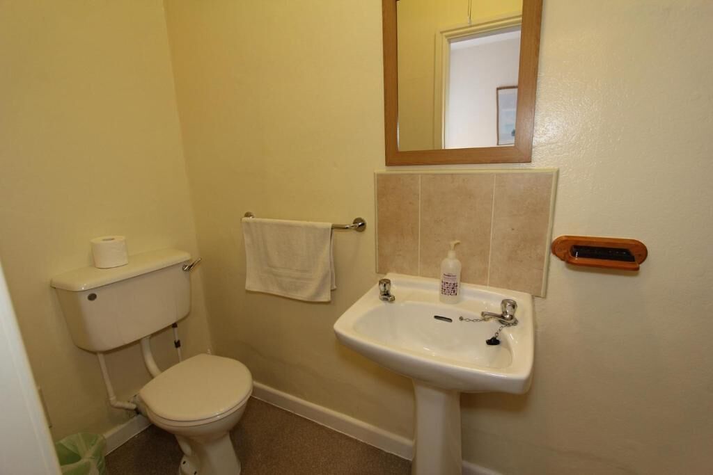 A small bathroom with a toilet, sink, and a mirror above the sink.
