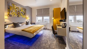 A modern hotel room with a large bed, a desk, a chair, and a large window with a view. - Escape Boutique B&B (Llandudno)