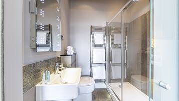 Ein modernes Badezimmer mit Duschkabine aus Glas, einem weißen Waschbecken und einer Toilette.