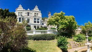 A large, ornate building with a white facade and multiple windows, surrounded by lush greenery and a well-maintained garden. - Escape Boutique B&B (Llandudno)