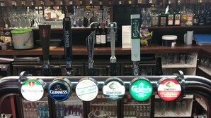 Un bar con diversi rubinetti per birra e bottiglie sullo sfondo.