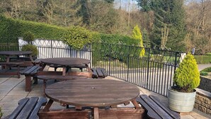 Un tavolo da picnic in legno con panche, circondato da una recinzione in metallo e vasi di piante.