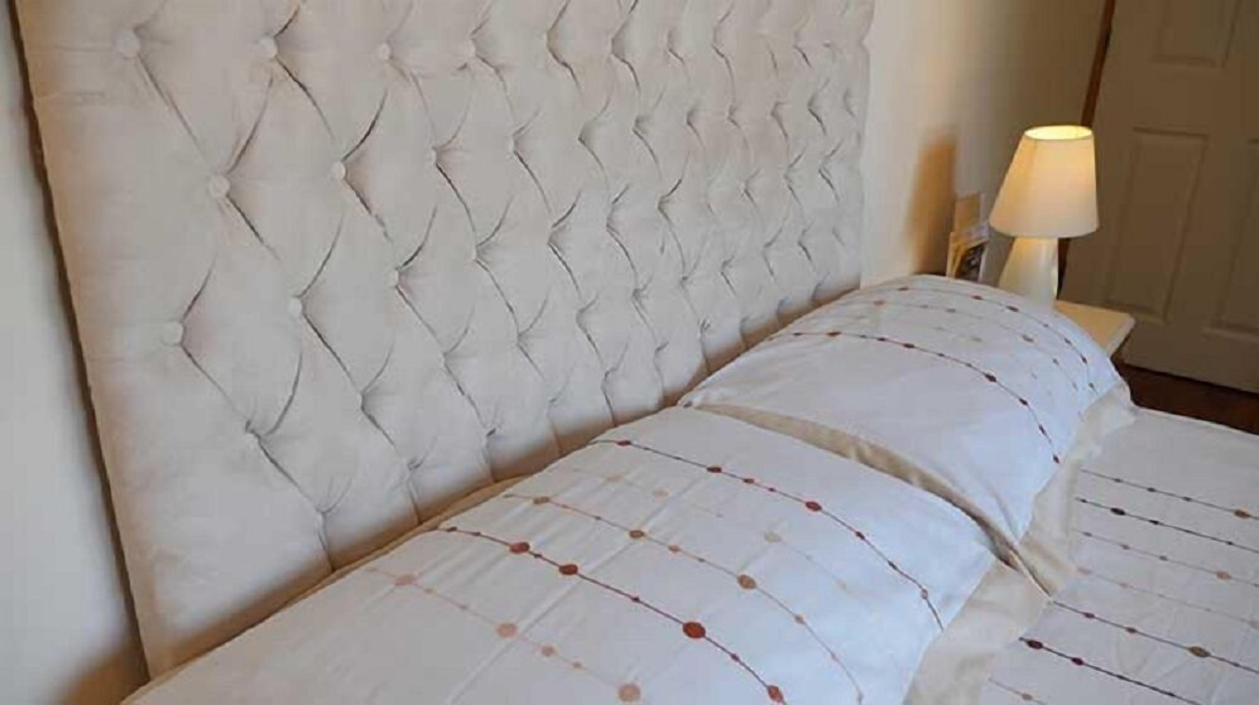 Un lit doté d’une tête de lit capitonnée et d’une couvre-lit à motifs.