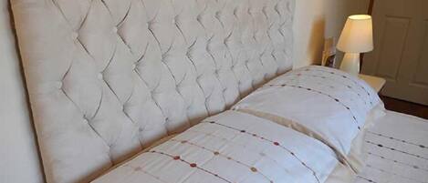 Un lit doté d’une tête de lit capitonnée et d’une couvre-lit à motifs.