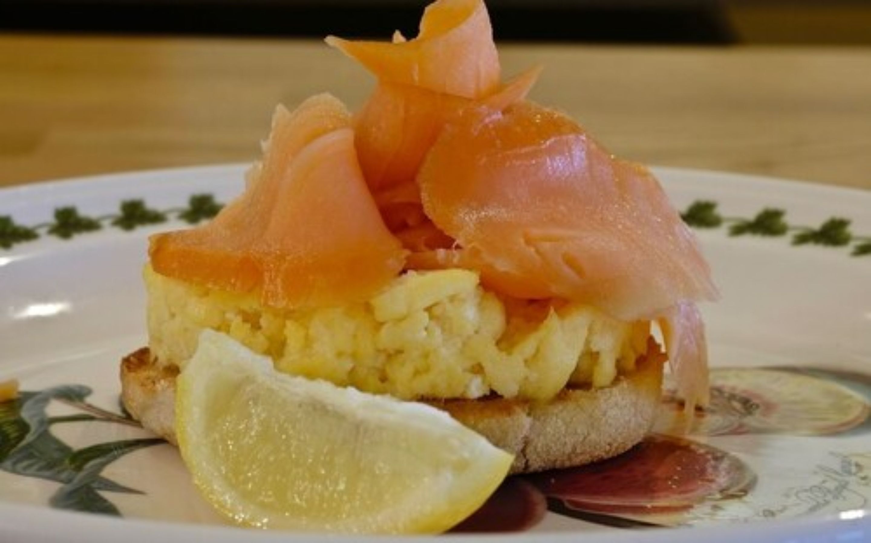 Ein Teller mit Rührei, geräuchertem Lachs und einer Zitronenspalte.