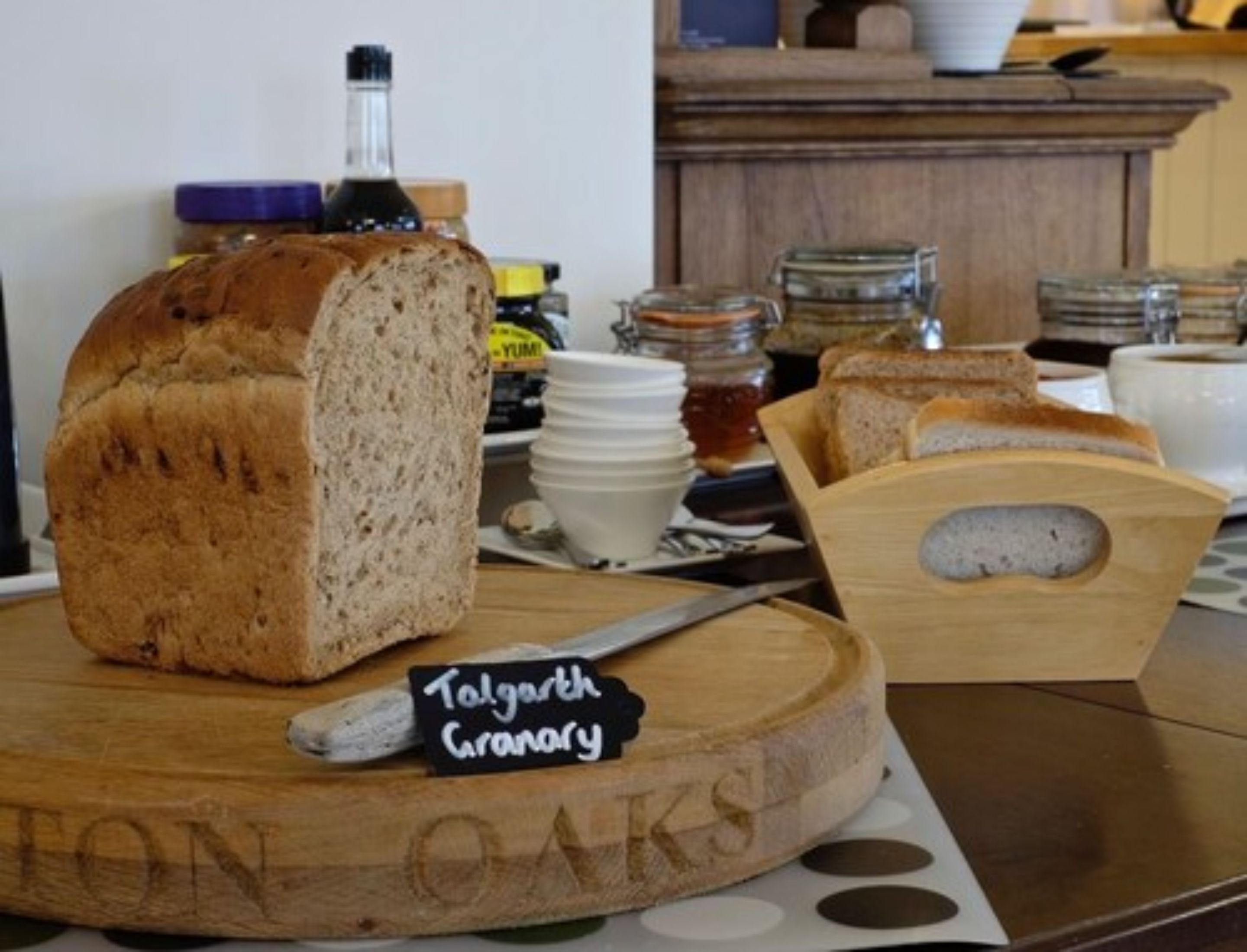 Una barra de pan Talgarth Granary sobre una tabla de madera con un cuchillo y una etiqueta.