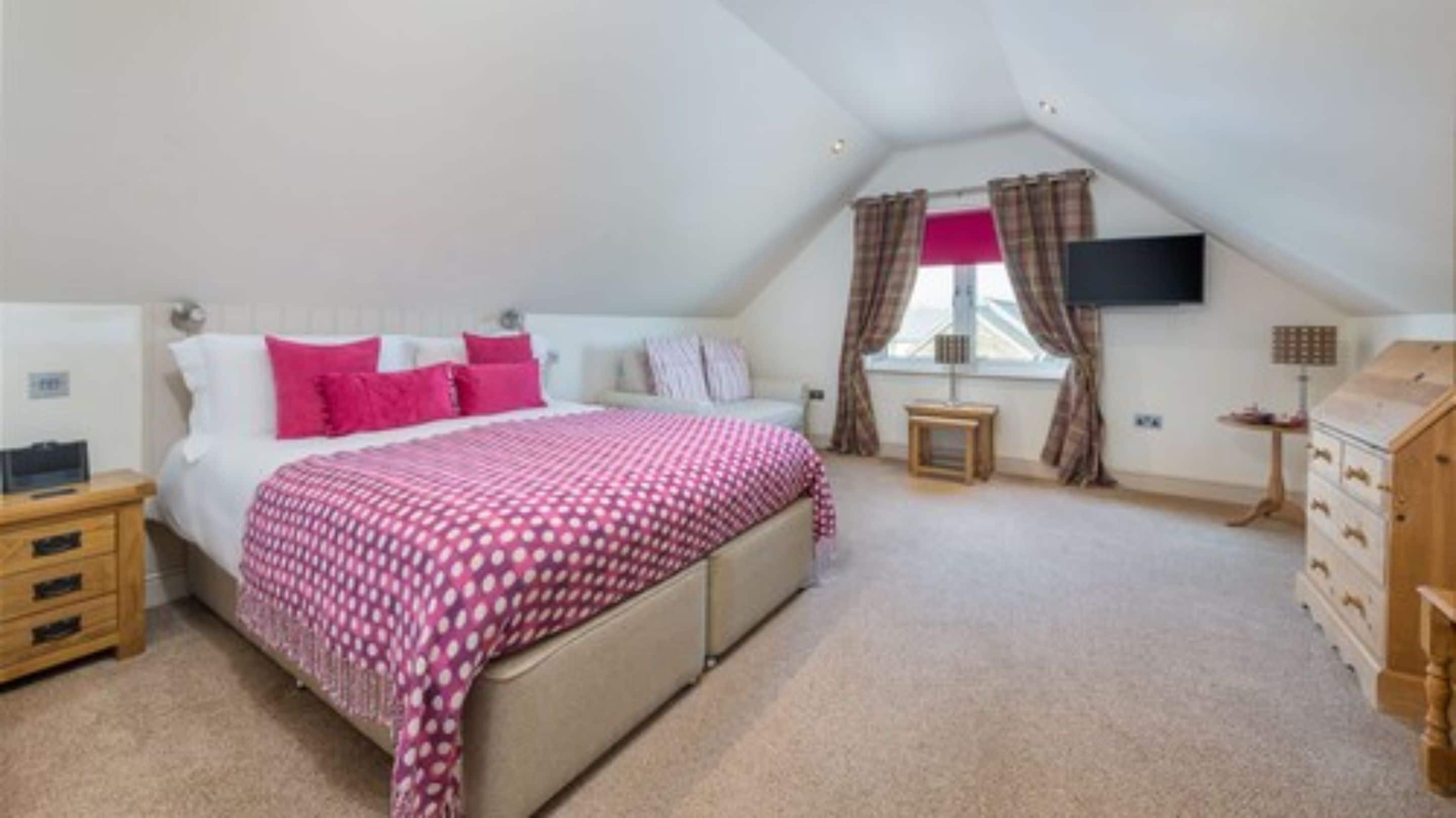 A bedroom with a bed, bedside tables, a dresser, and a window with curtains.
