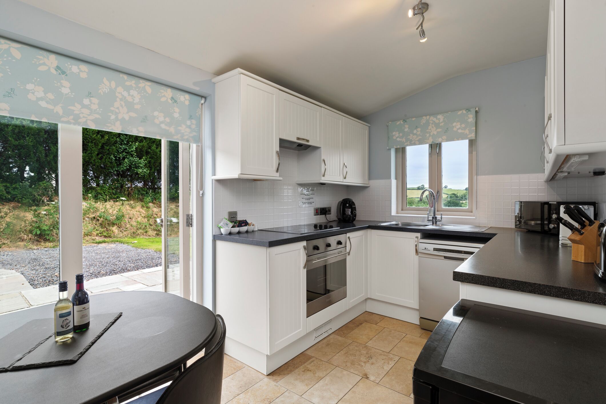 Een moderne keuken met witte kasten, een zwart aanrecht en uitzicht op de omgeving.