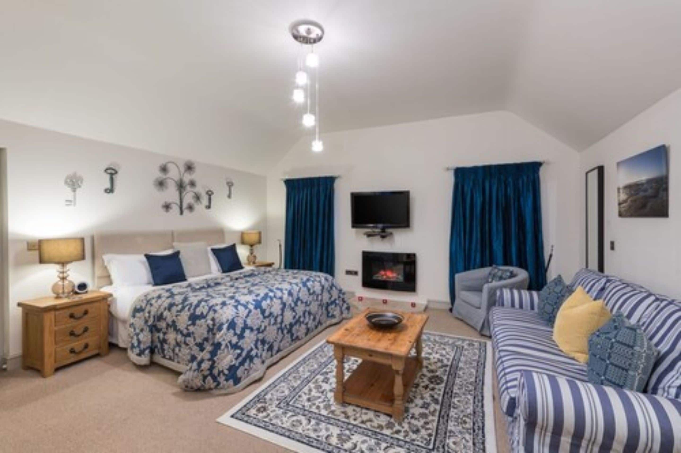 Een slaapkamer met een bed, nachtkastje, lamp en een televisie.