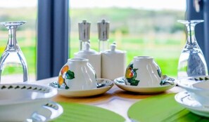 Una mesa dispuesta con tazas y platillos blancos, un tetera y un azucarero.