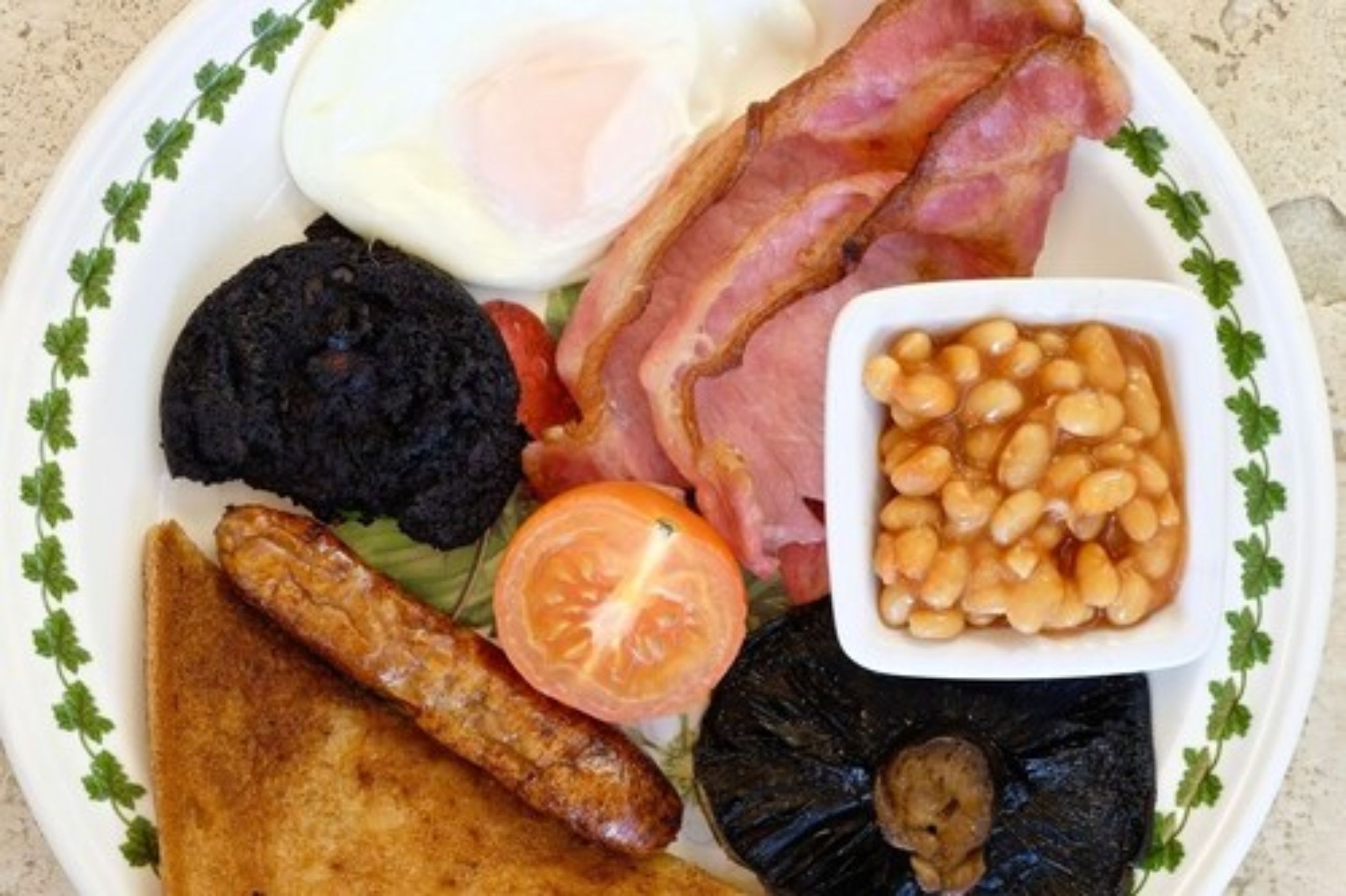 A plate with various breakfast items including bacon, eggs, beans, toast, and sausages.