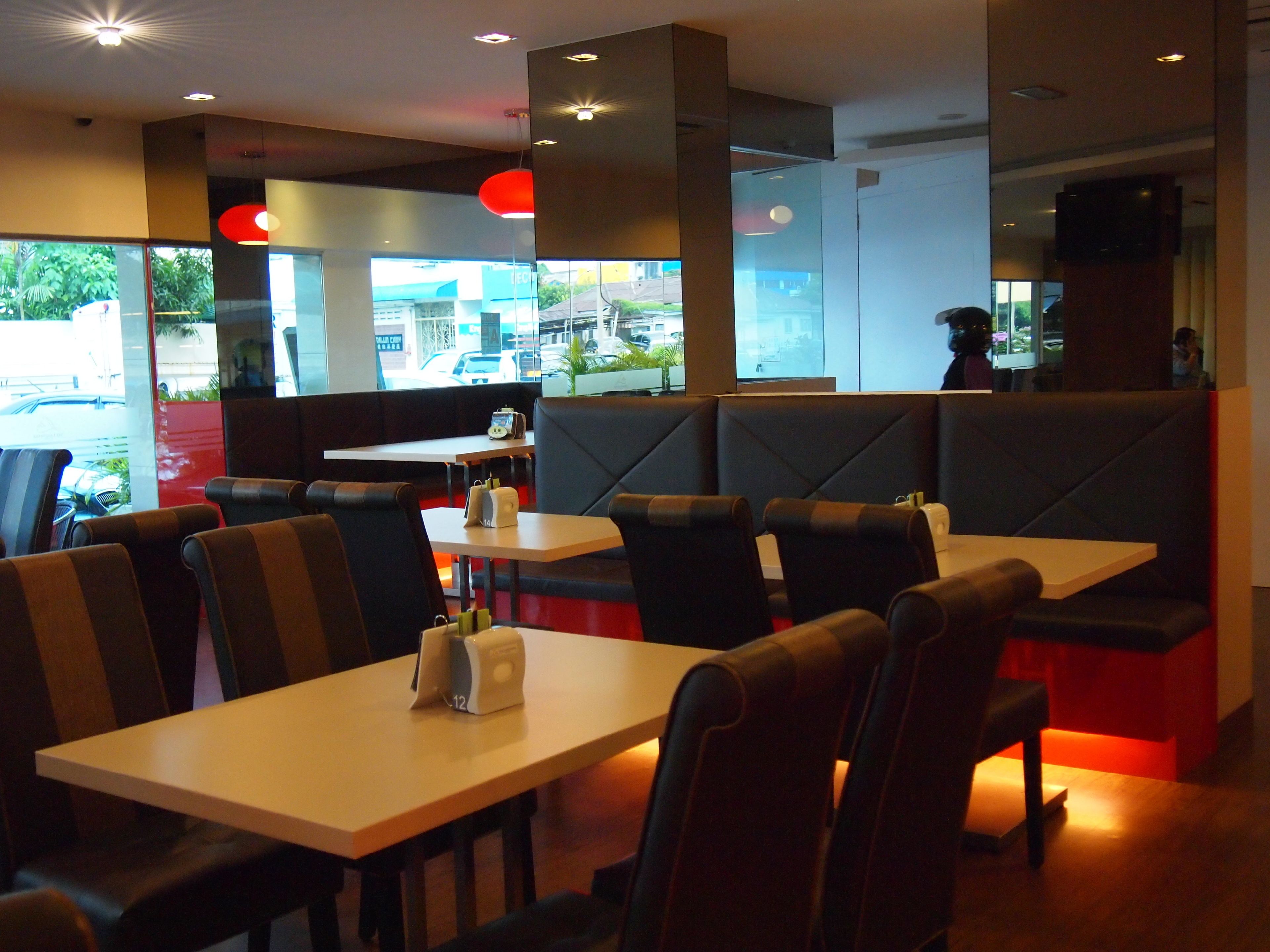 A restaurant interior with booths and tables, some with menus and condiments.