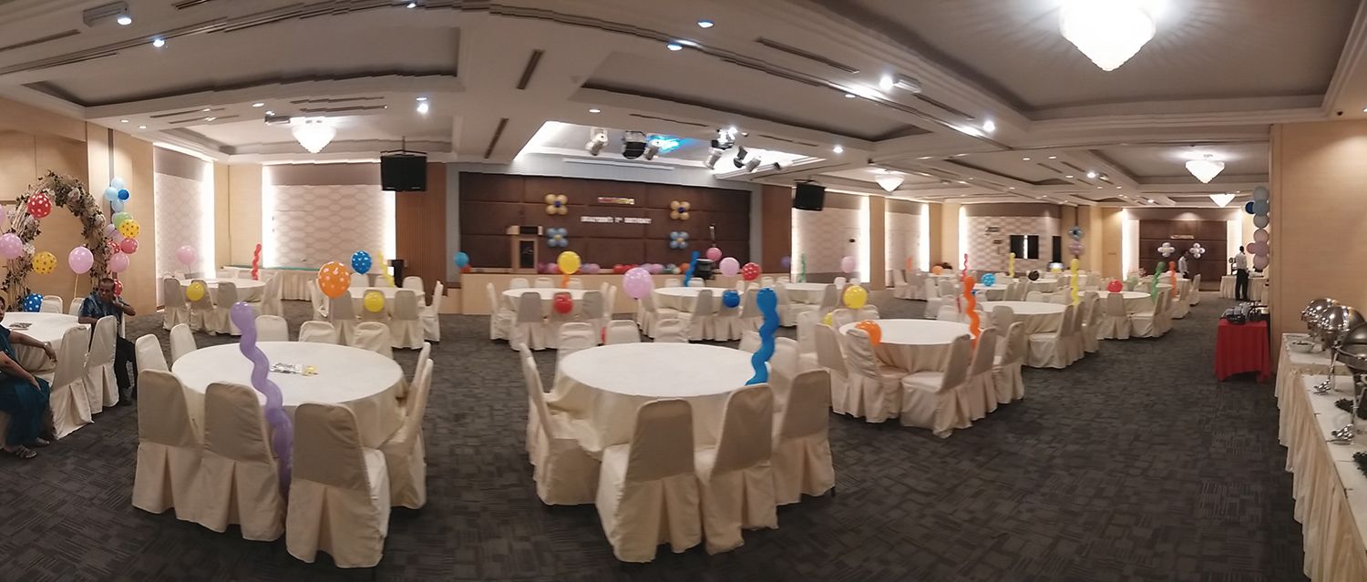 Une salle de banquet avec des tables rondes recouvertes de nappes blanches, disposées en rangées.