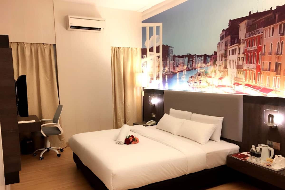 A hotel room with a bed, a desk, an air conditioner, and a cityscape mural on the wall.