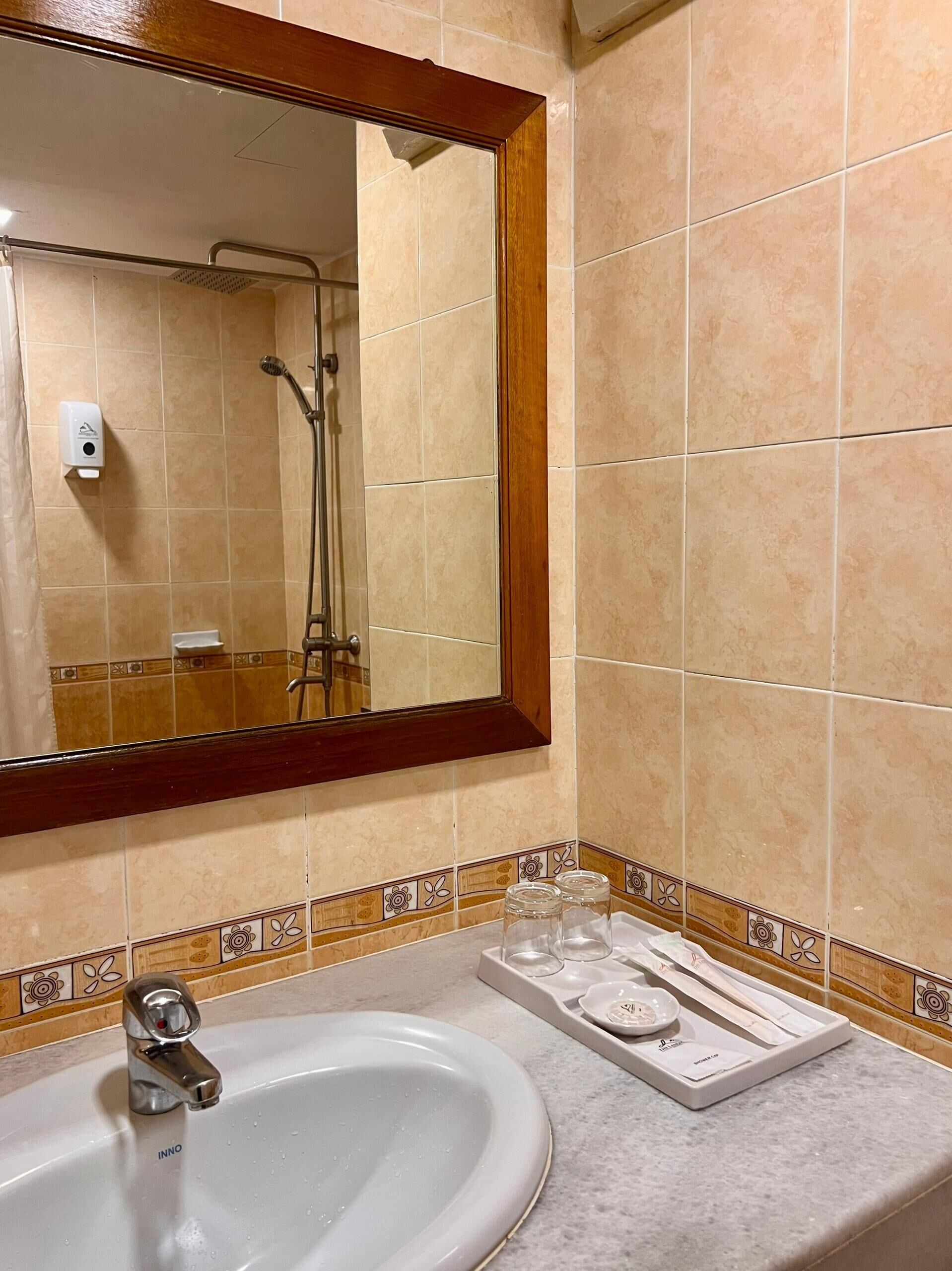 A bathroom with a large mirror, a sink, and a shower.