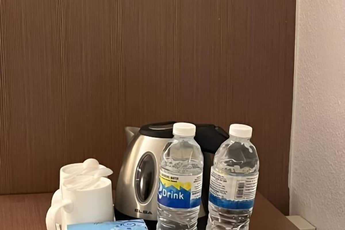 A kitchenette with a coffee maker, two water bottles, and a white mug.