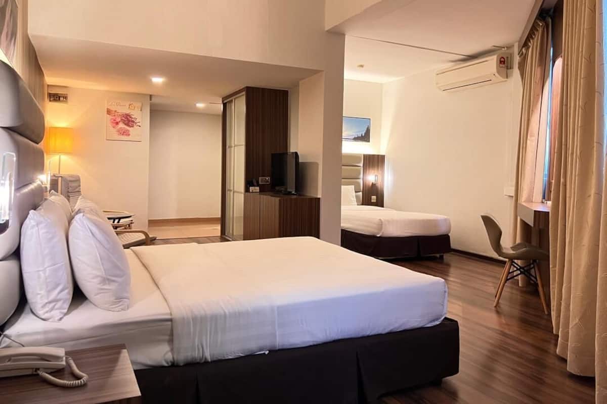 A hotel room with a large bed, a desk with a telephone, a TV, and a chair.