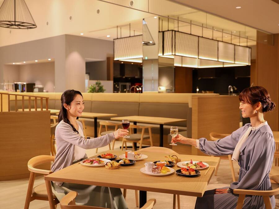 A modern dining area with wooden tables and chairs, a variety of dishes on the tables, and a contemporary interior design with pendant lighting.