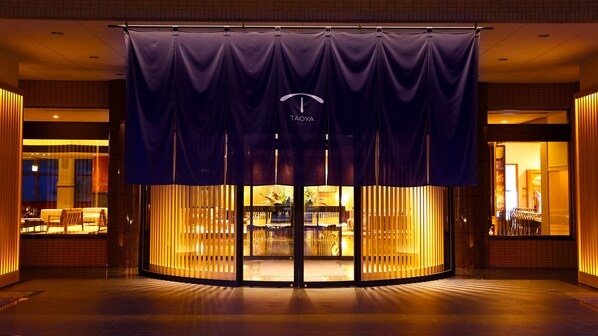 A hotel entrance with a dark blue curtain, a glass door, and a warm interior lighting. - TAOYA Kisoji  (Nagiso)