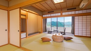 A traditional Japanese room with tatami flooring, a low table with cushions, and a view of mountains through large windows. - TAOYA Kisoji  (Nagiso)