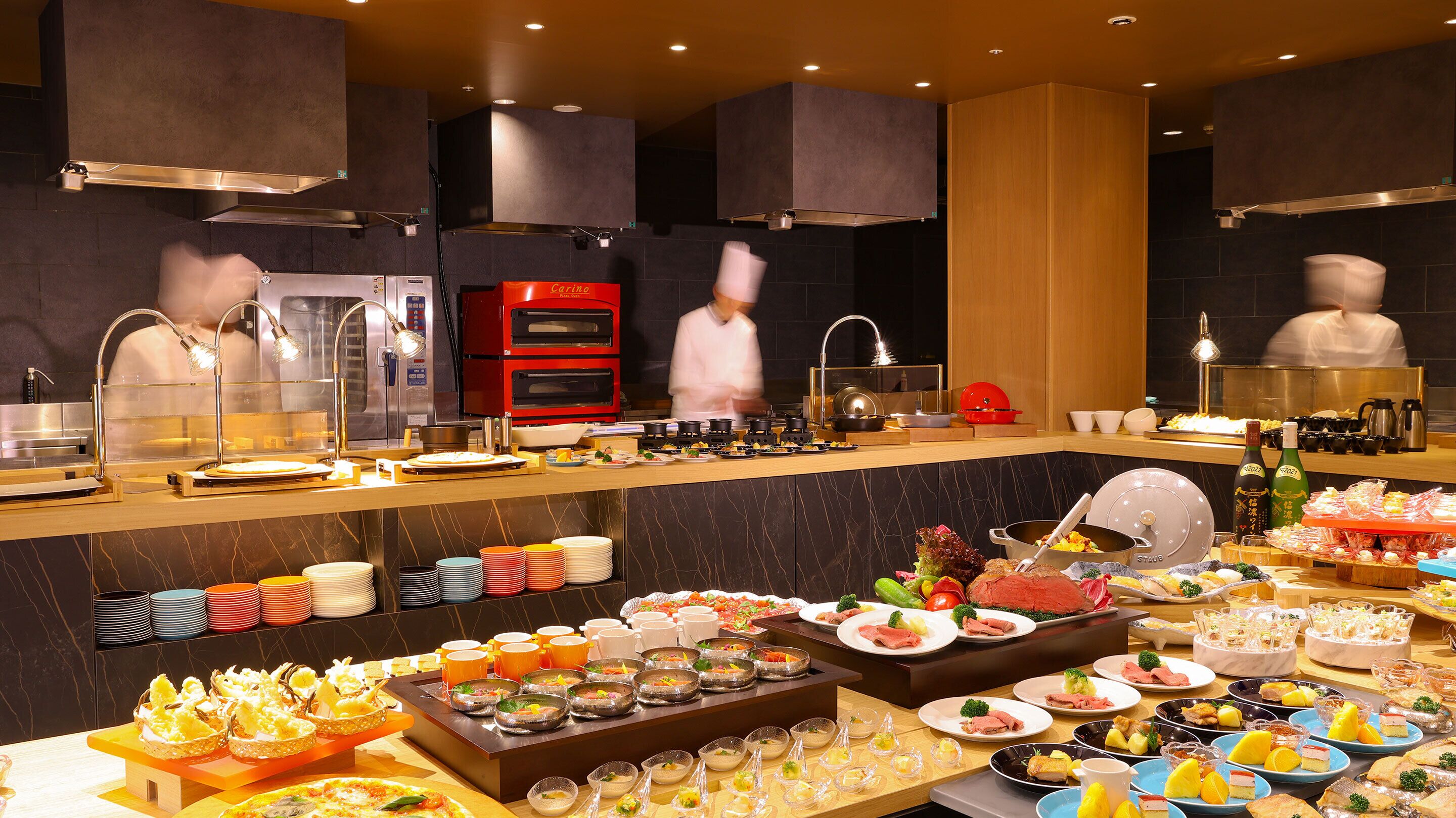 A buffet setup with various food items and a chef in motion.