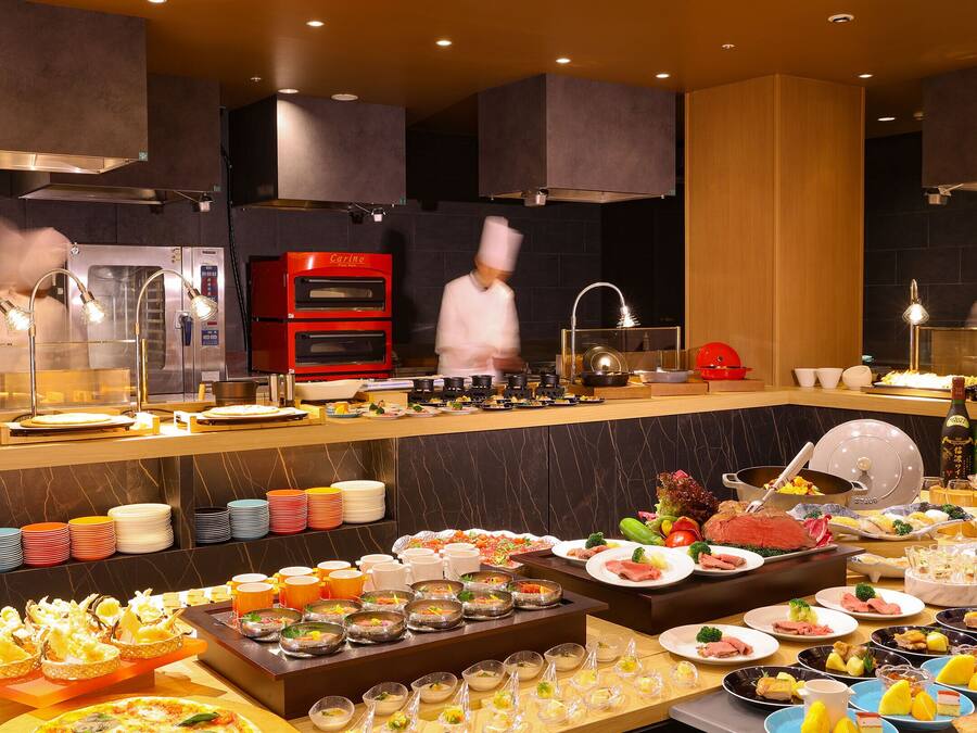 A buffet setup with various food items and a chef in motion.