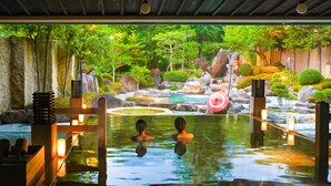 A hot spring area with two people in the water, surrounded by rocks and greenery. - TAOYA Kisoji  (Nagiso)