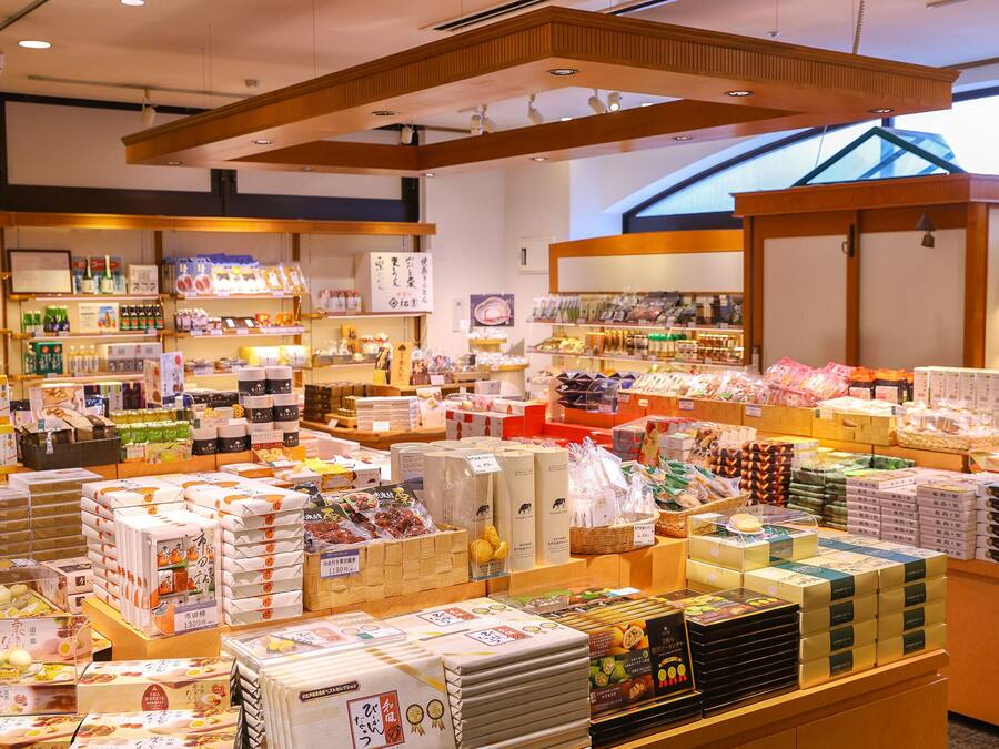 A well-lit store with various packaged goods, including food items and household products, displayed on shelves and counters.