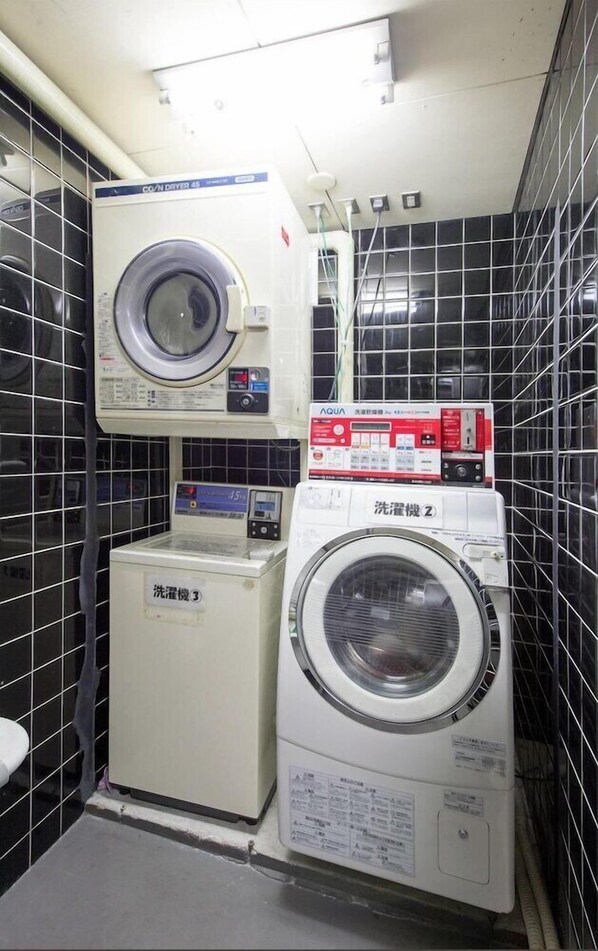 A laundry room with two washing machines, a dryer, and a water heater.