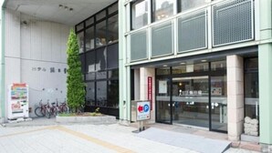 A building with a modern entrance, a parking sign, and bicycles parked outside. - Iidaya (Matsumoto)