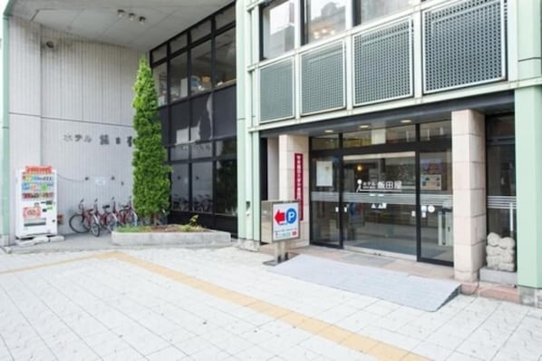Un edificio con entrada moderna, un letrero de estacionamiento y bicicletas aparcadas afuera.
