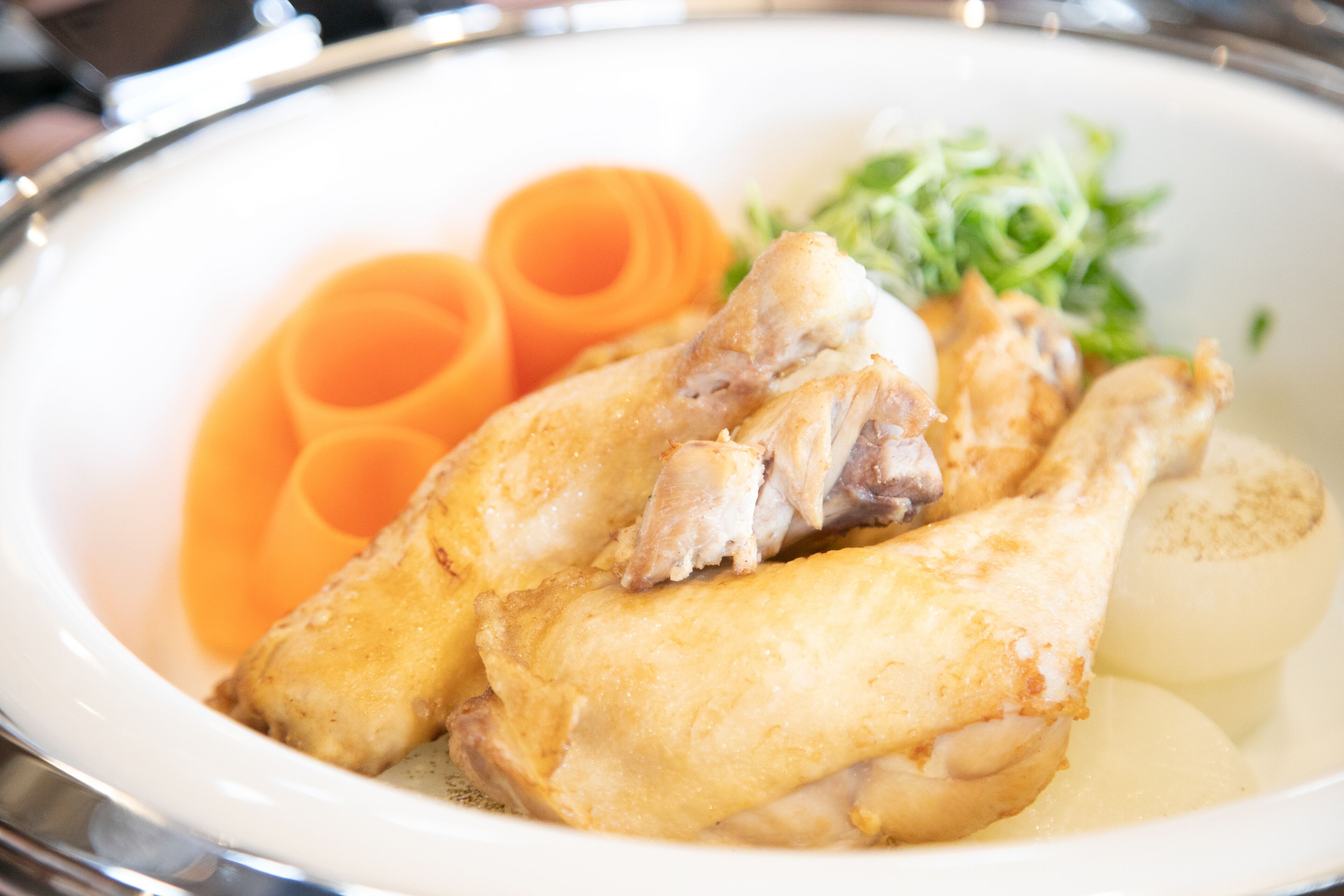 A plate with chicken, carrots, and greens.