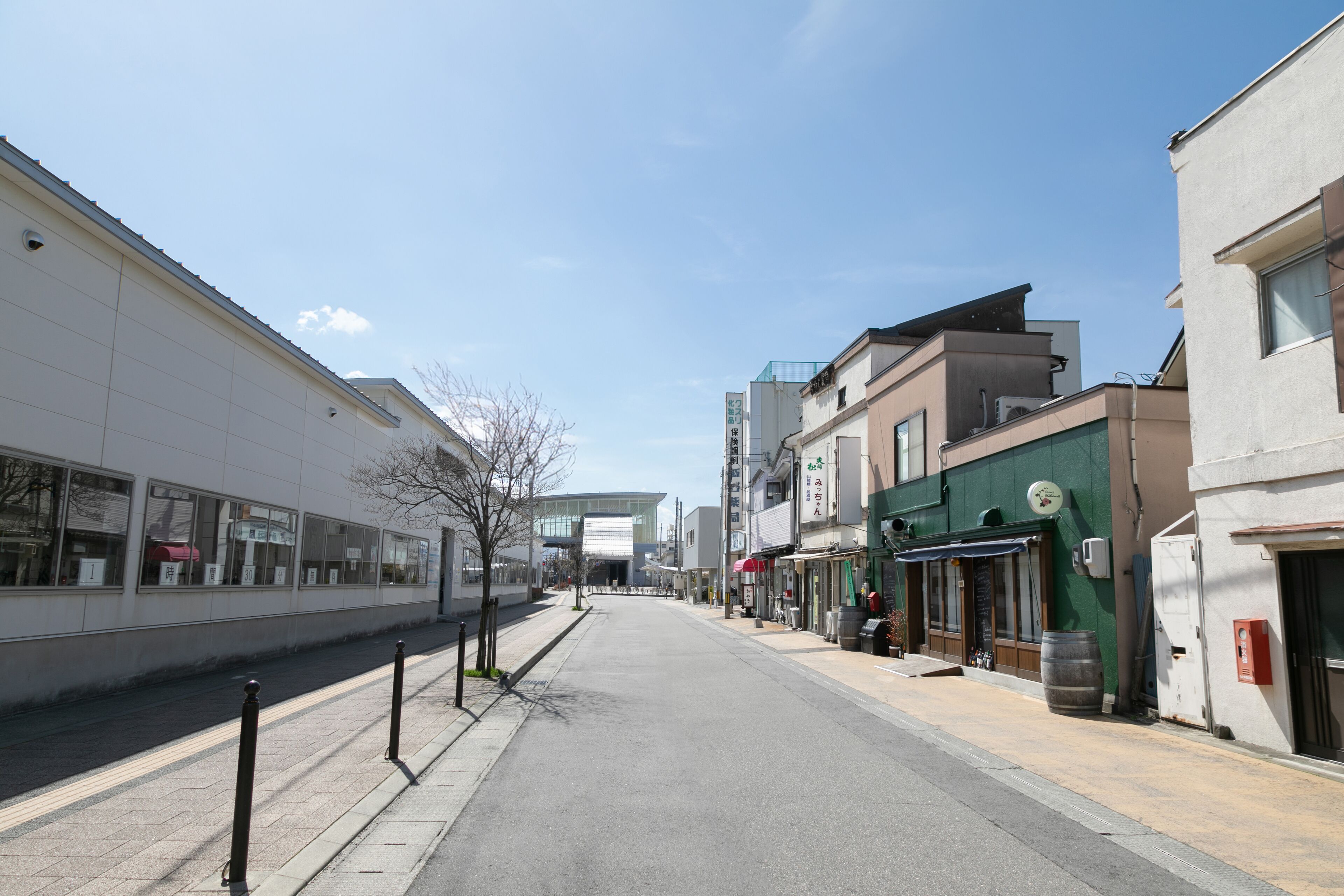 A street with modern buildings, a sidewalk, and a clear sky.
