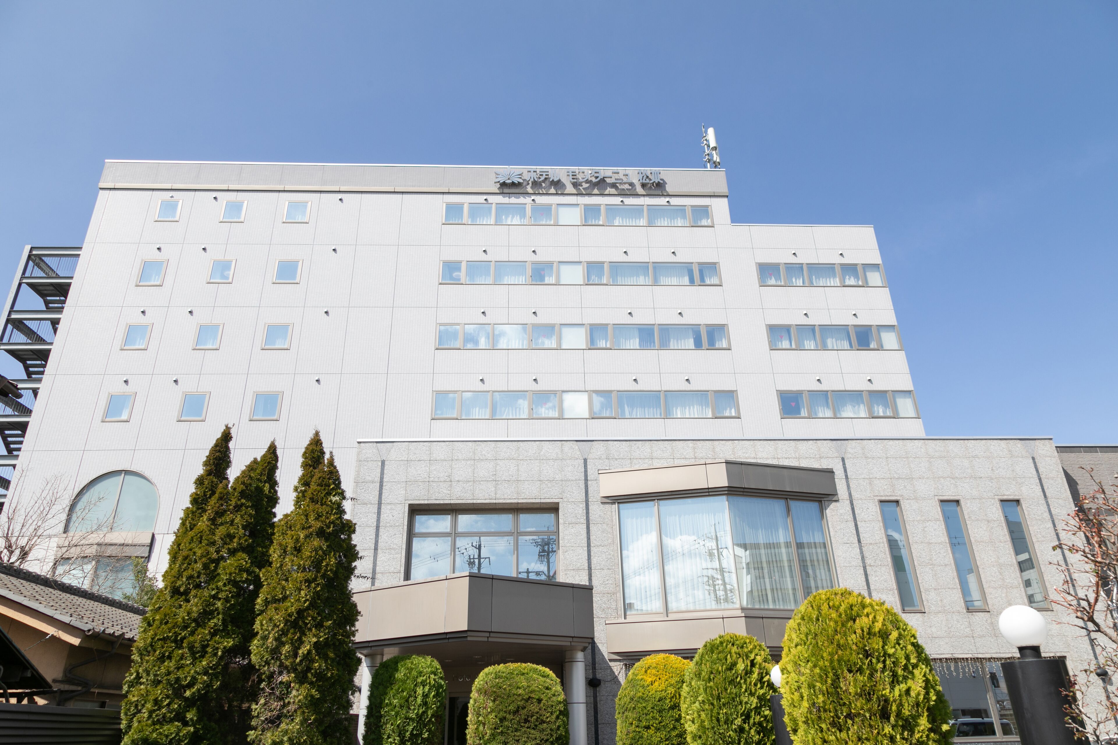 Un hotel de varios pisos con un diseño moderno, que cuenta con una entrada destacada con un área cubierta y varias ventanas en cada planta.