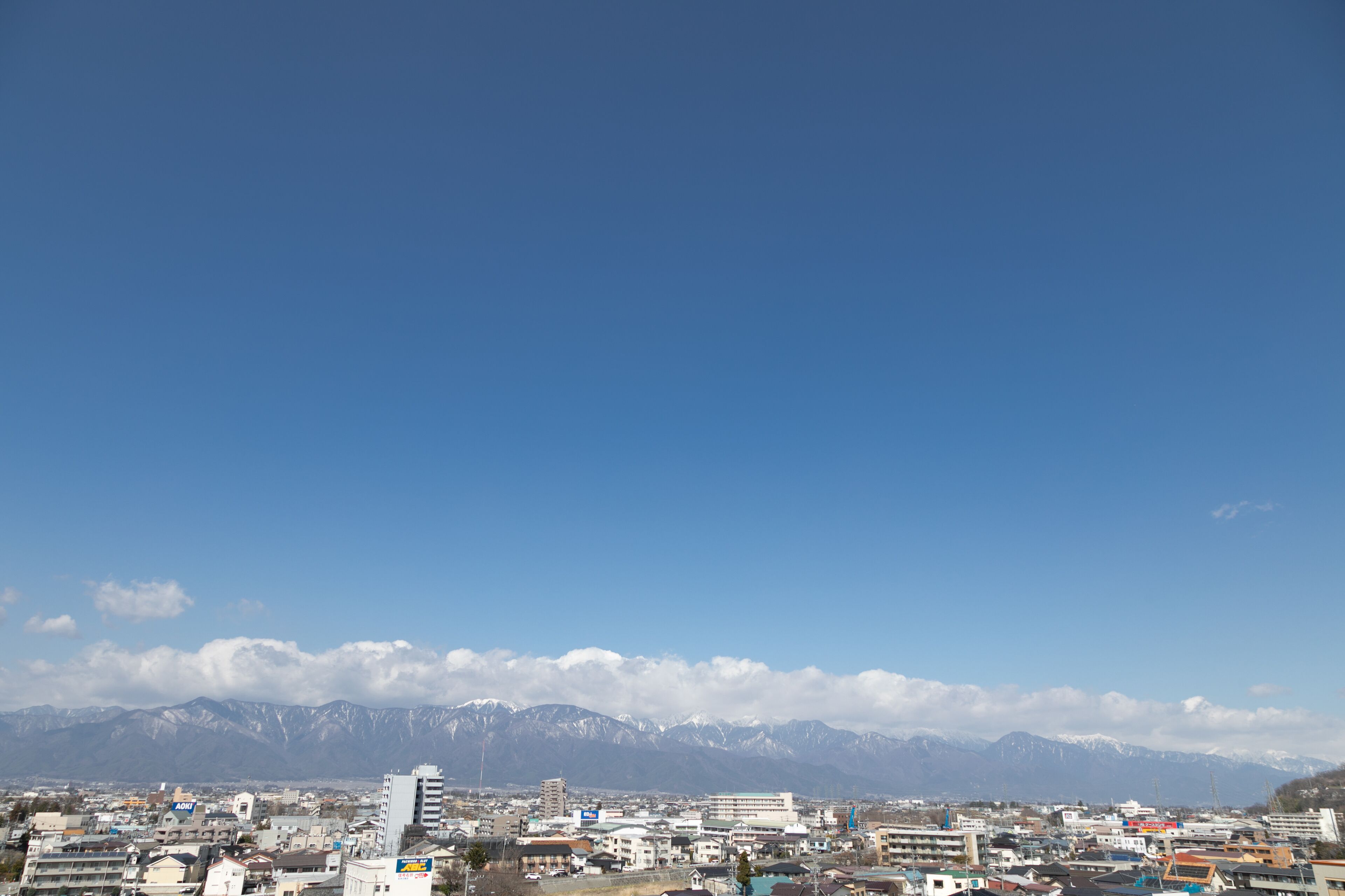 Un paisaje urbano con edificios y una cadena montañosa al fondo.