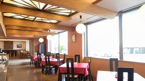 A restaurant interior with wooden beams, red tablecloths, and chairs. - Hotel Montagne Matsumoto (Matsumoto)