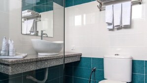Een moderne badkamer met een douchecabine van glas, een witte wastafel en een toilet.