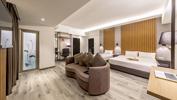 Een moderne hotelkamer met een gebogen bank, een groot bed, een bureau met een laptop en een kledingkast.