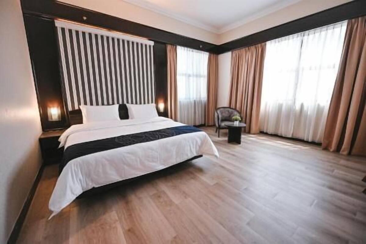 A modern hotel room with a large bed, a chair, and a small table.