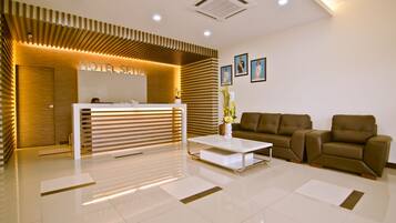 A hotel reception area with a modern design, featuring a reception desk, sofas, and a coffee table.