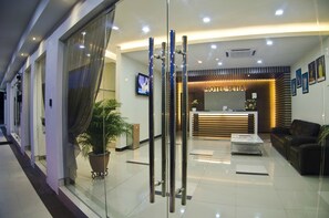 A hotel reception area with a modern design, featuring a reception desk, seating area, and a large potted plant. - Hotel Setia (Kluang)