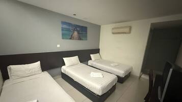 Quarto de hotel com três camas, um quadro na parede, aparelho de ar condicionado e televisão.