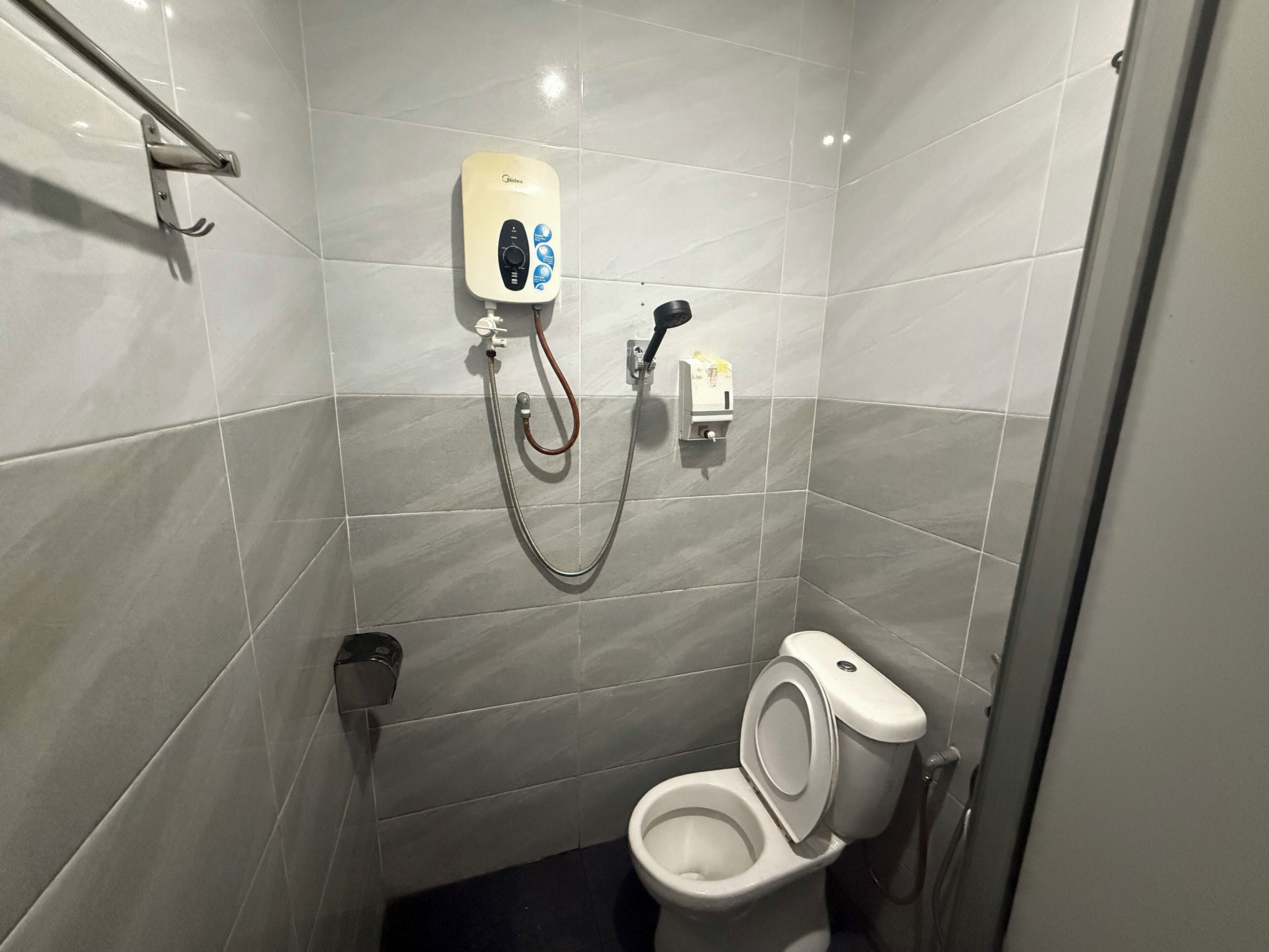 Un baño pequeño y moderno con un inodoro, un secador de manos y un dispensador de toallas de papel.