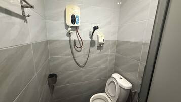 Un baño pequeño y moderno con un inodoro, un secador de manos y un dispensador de toallas de papel.