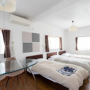 Habitación de hotel con dos camas, una mesita de vidrio y vistas a la ciudad.