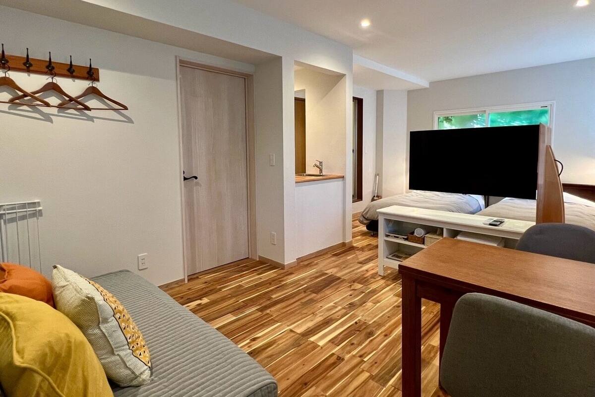 Une chambre d’hôtel de taille réduite, comprenant un lit, un bureau, une chaise, un téléviseur et un porte-manteau.