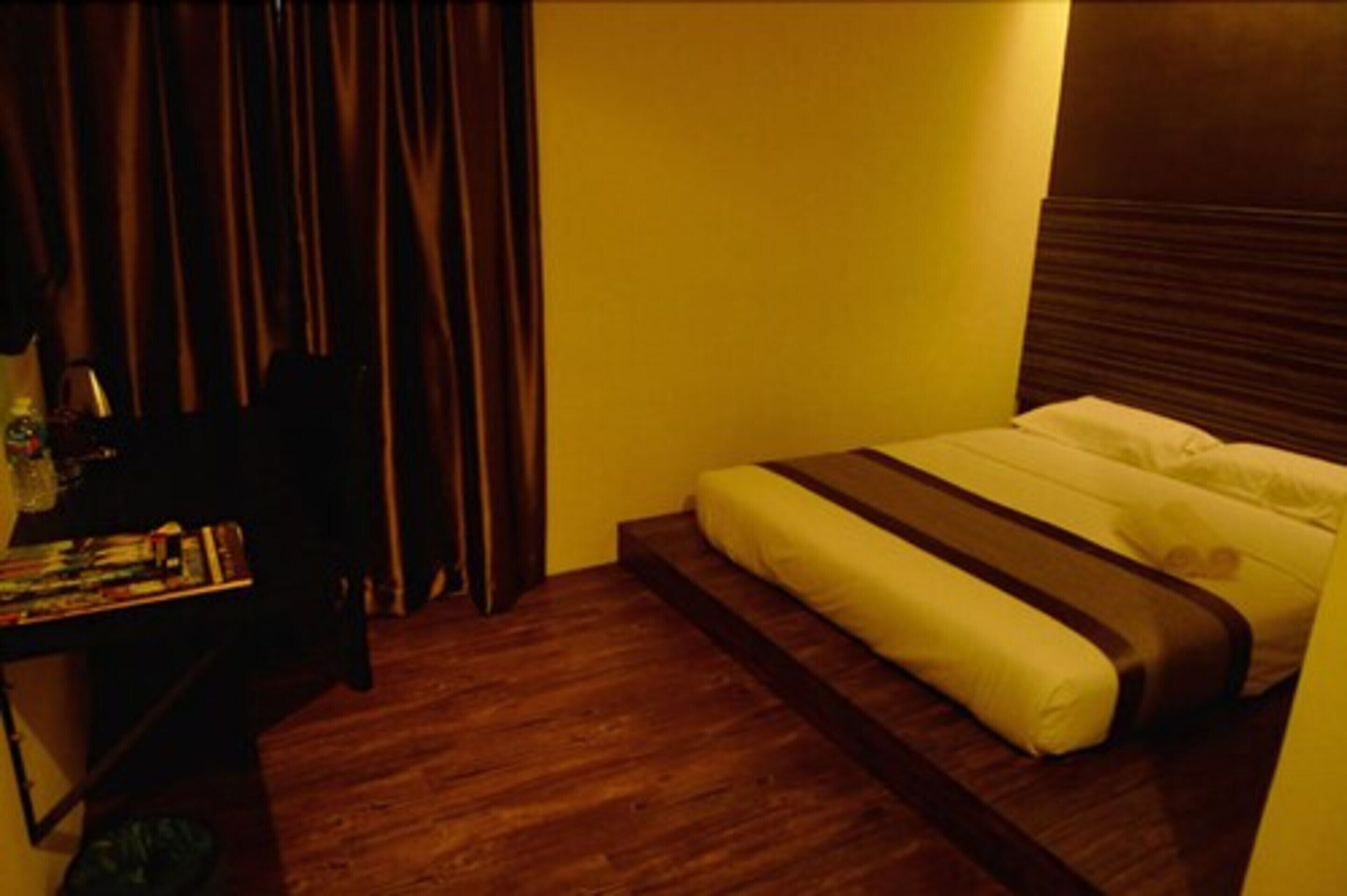A bedroom with a bed, a small table with books, and a curtain.