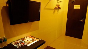 A room with a flat-screen TV mounted on the wall, a small table with magazines, and a door with a lock. - Hotel Austin Paradise - Pulai Utama (Johor Bahru)