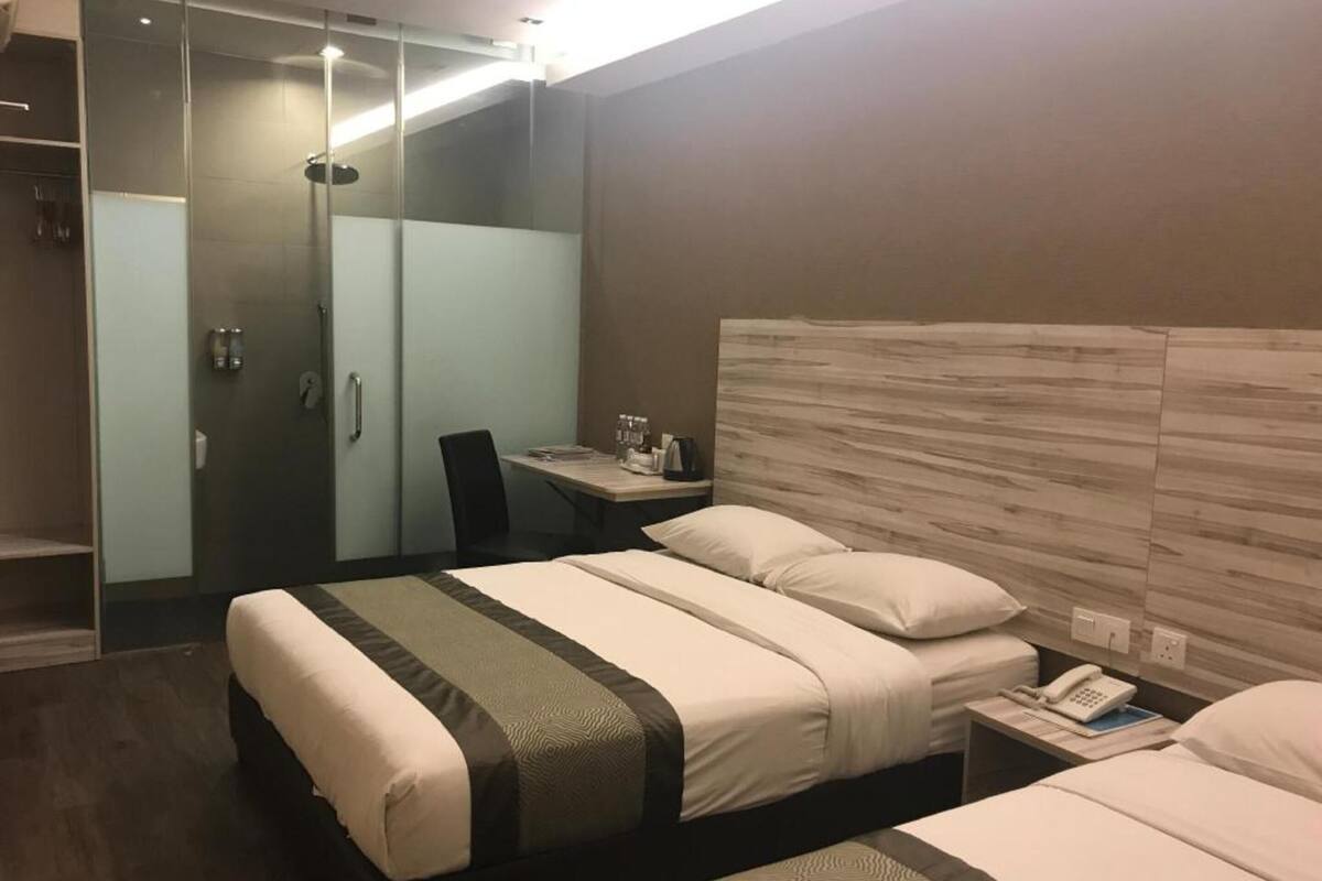Een hotelkamer met twee bedden, een bureau, een stoel, een douche en een telefoon op het nachtkastje.