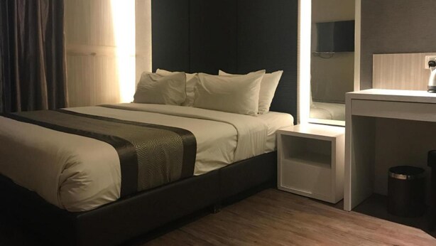 A modern hotel room with a large bed, bedside tables, a mirror, and a small trash bin. - Hotel Austin Paradise - Pulai Utama (Johor Bahru)